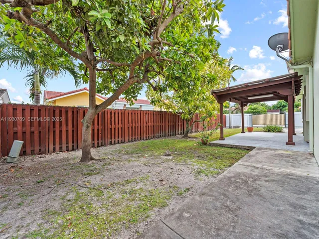 a view of a backyard with wooden fence and a large tree