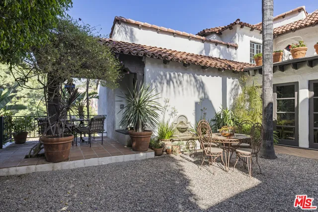 a view of a patio with table and chairs potted plants and a large tree