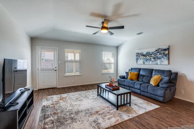 a living room with furniture a ceiling fan and a window