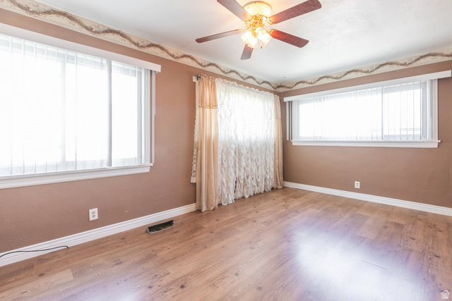 59 East Pinehurst Street Tooele, UT 84074 - Photo 10 of 22 Spacious interior room featuring wood-finish flooring, two large windows with white blinds, and a ceiling fan with integrated lighting