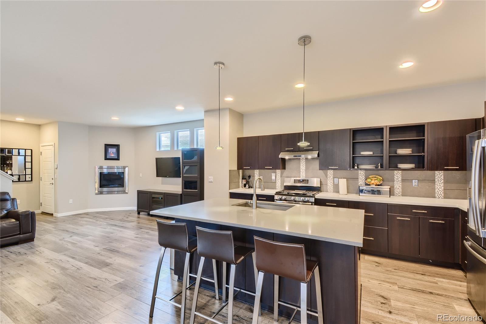 3319 Cranston Circle Highlands Ranch, CO 80126 - Photo 8 of 28 a kitchen with stainless steel appliances granite countertop a stove top oven a sink dishwasher a dining table and chairs with wooden floor