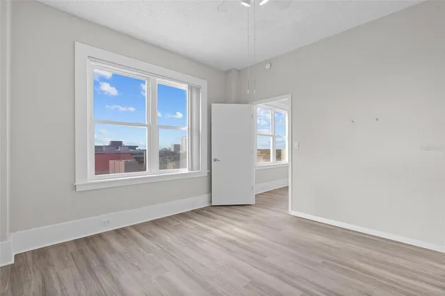 an empty room with wooden floor and windows