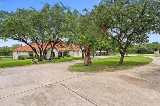a view of a house with a big yard and large trees