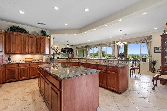 a kitchen with stainless steel appliances granite countertop a table chairs sink and cabinets