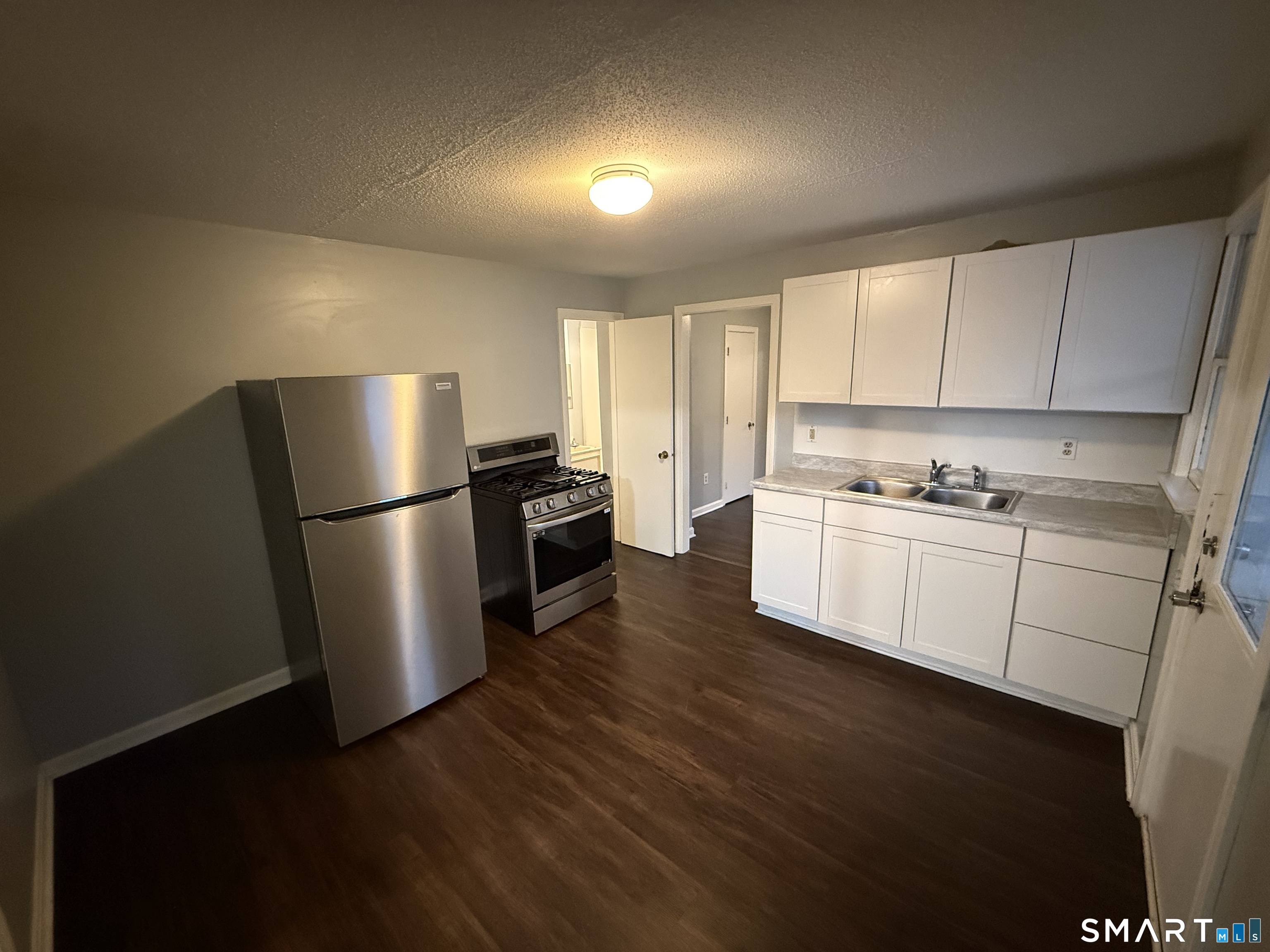 a kitchen with a refrigerator a sink dishwasher a stove and white cabinets with wooden floor