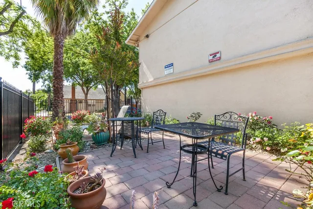 a backyard with table and chairs potted plants and a large tree