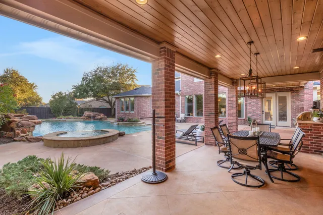 a view of a patio with table and chairs potted plants and floor to ceiling window