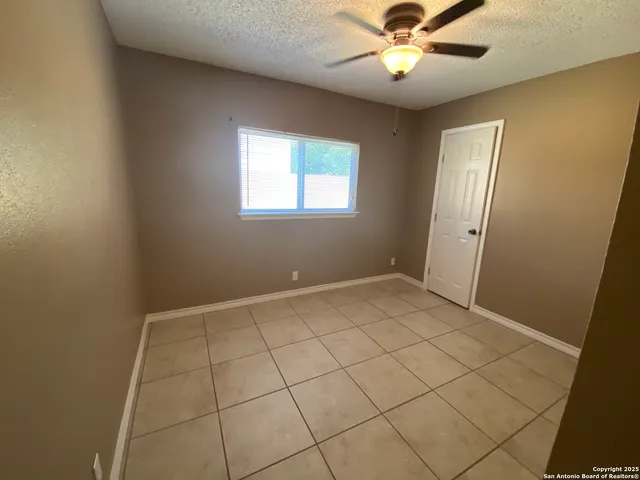 a view of an empty room and chandelier fan