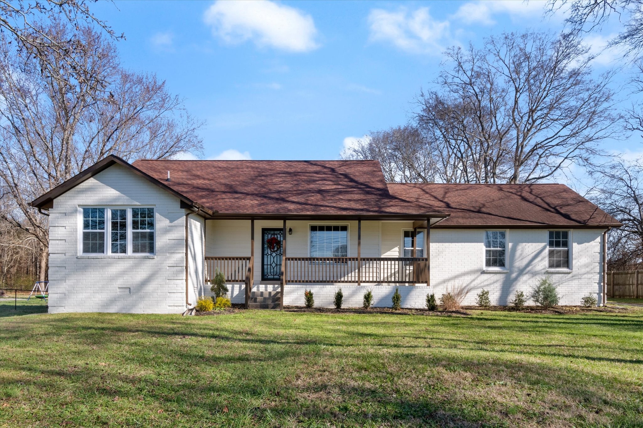 a front view of a house with a garden and trees