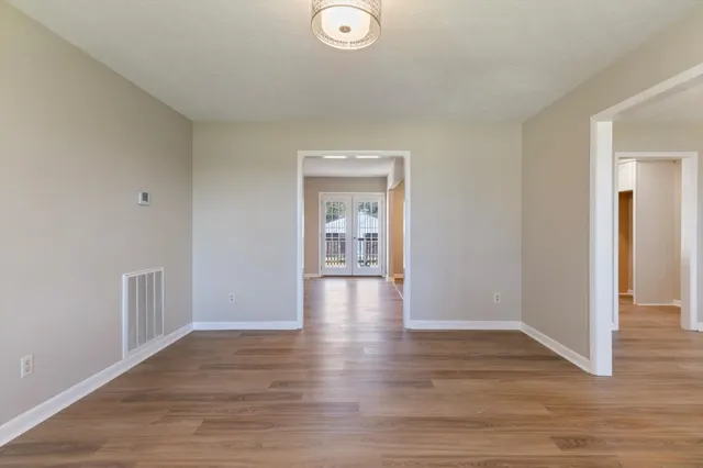 a view of an empty room with wooden floor fireplace and a window