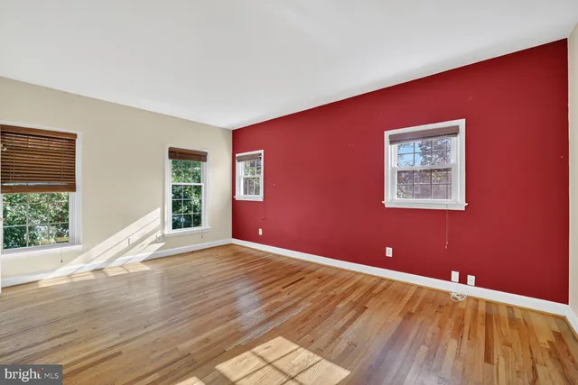 an empty room with wooden floor closet and windows