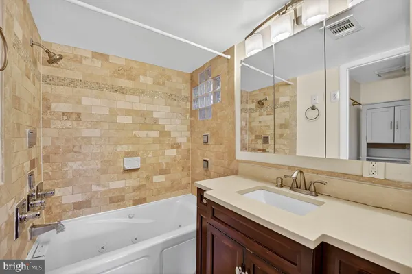 a bathroom with a granite countertop sink and a bathtub