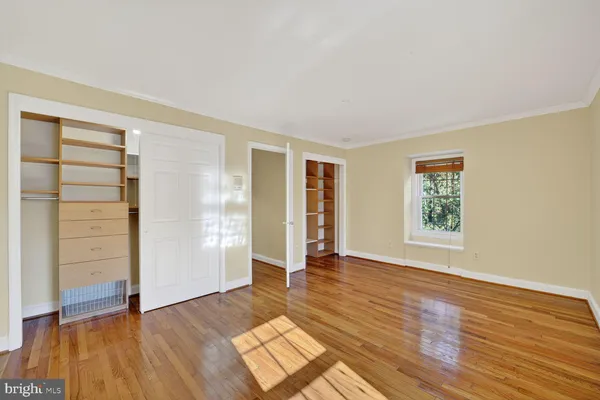 an empty room with wooden floor closet and windows