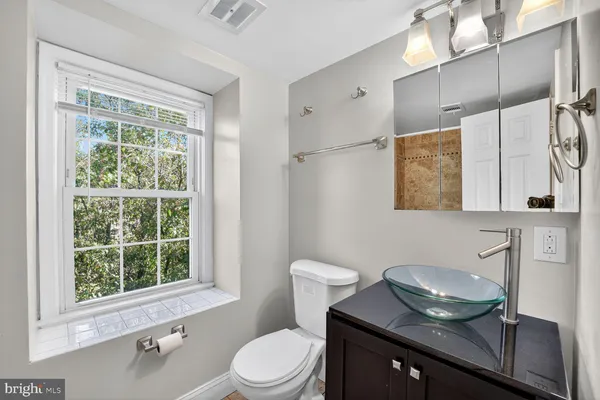 a bathroom with a granite countertop sink mirror vanity and toilet