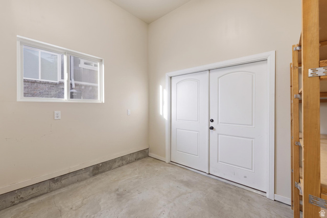 441 South 2080th Street East Springville, UT 84663 - Photo 41 of 64 Concrete flooring with a perimeter baseboard, a window with horizontal blinds, and a pair of white paneled doors with black hardware