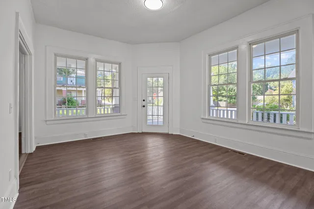 an empty room with wooden floor & a bathroom