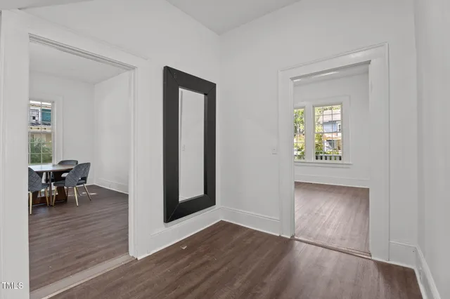 a bed sitting in a spacious bedroom next to a window and wooden floor