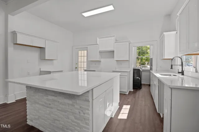 a kitchen with kitchen island granite countertop a sink cabinets and window