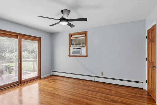 an empty room with wooden floor fan and windows
