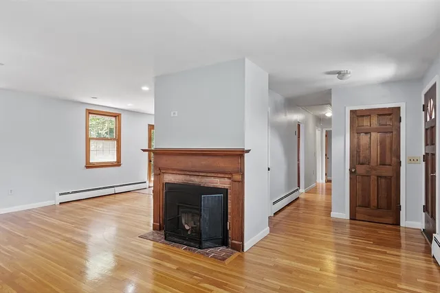 a view of a livingroom with wooden floor and a fireplace