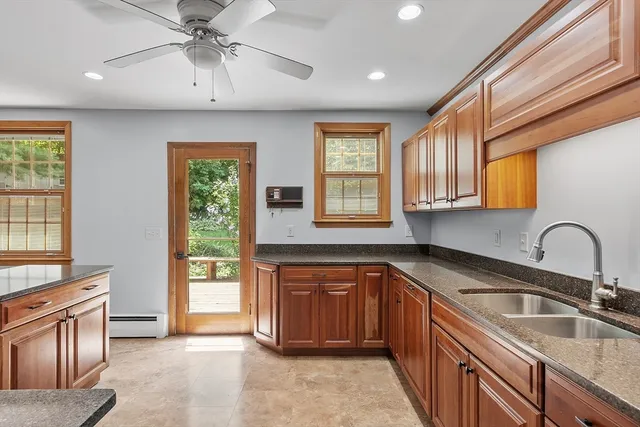 a kitchen with kitchen island granite countertop a sink appliances cabinets and a large window