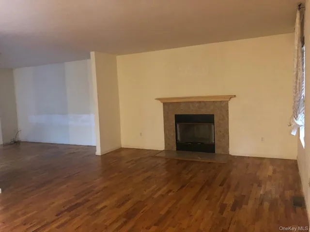 a view of an empty room with wooden floor and a fireplace