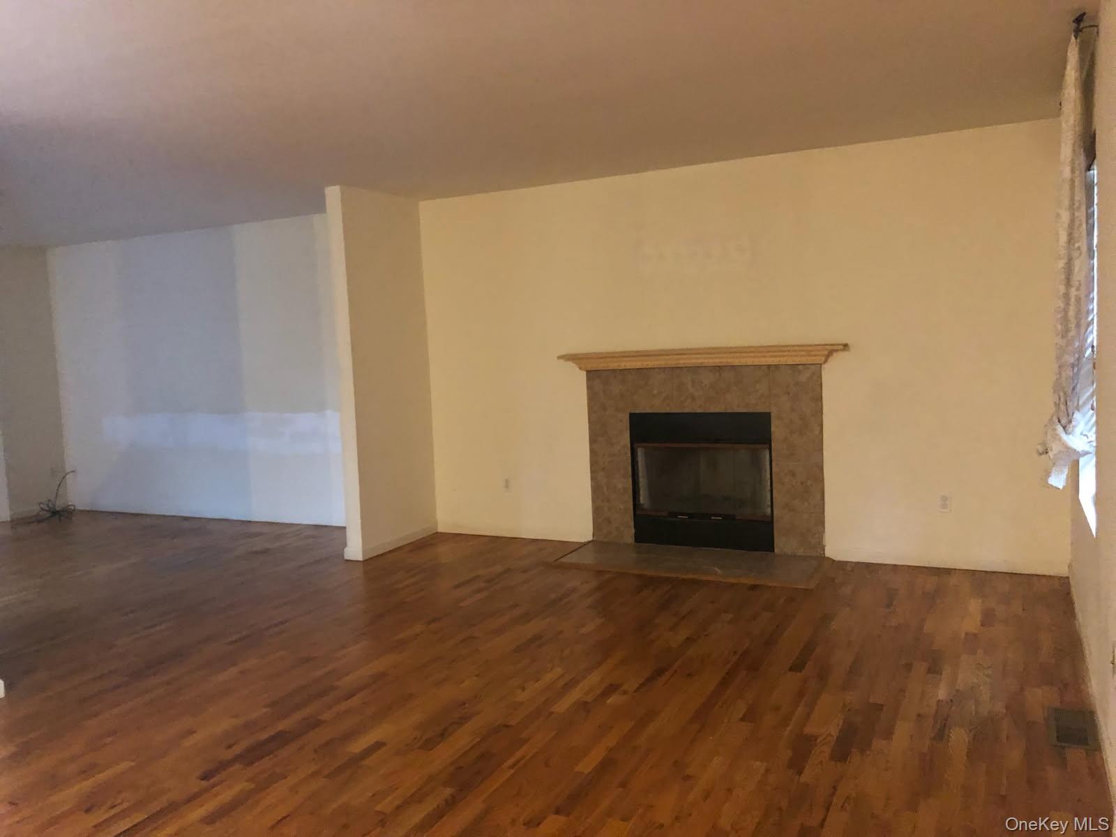 556 Airport Road Swan Lake, NY 12783 - Photo 5 of 22 a view of an empty room with wooden floor and a fireplace