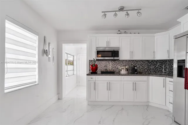 a kitchen with white cabinets and window