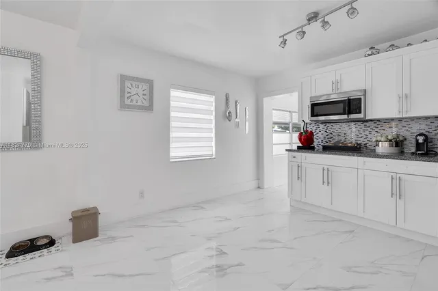 a kitchen with white cabinets and window