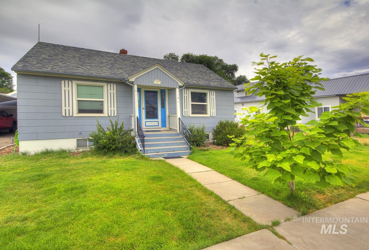 351 West Main Street South Vale, OR 97918 - Photo 33 of 33 Light blue siding exterior featuring white window trim and shutters, a bright blue front door, and a covered entryway