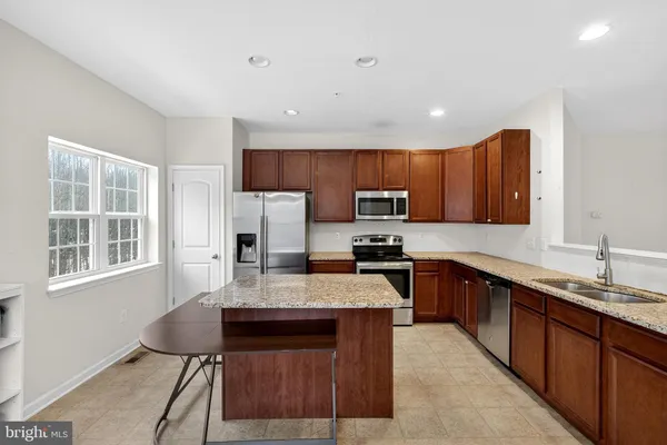 a large kitchen with granite countertop a stove top oven a sink dishwasher a dining table and chairs with wooden floor