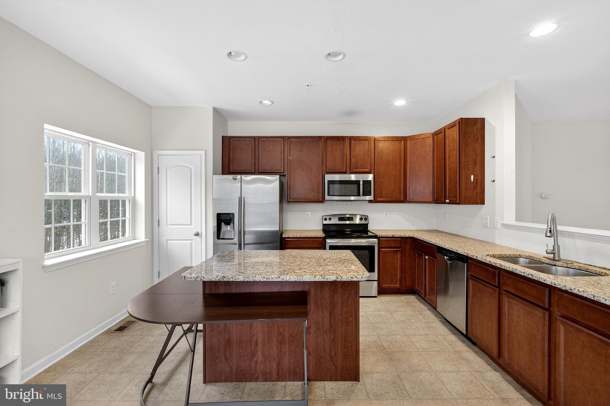 48 Munro Road Newark, DE 19711 - Photo 18 of 50 a large kitchen with granite countertop a stove top oven a sink dishwasher a dining table and chairs with wooden floor