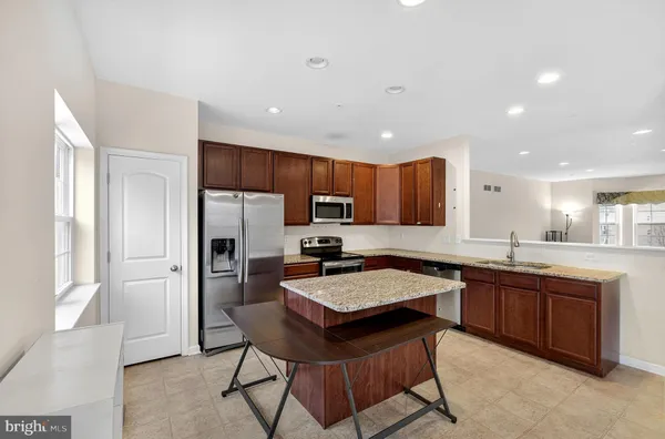 a kitchen with granite countertop a sink counter top space stainless steel appliances and cabinets