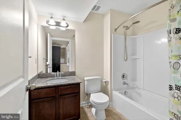 a bathroom with a granite countertop sink toilet mirror and bathtub