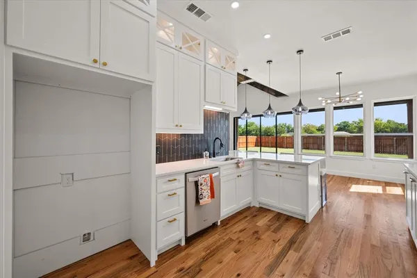 a kitchen with stainless steel appliances granite countertop a stove a sink and white cabinets with wooden floors