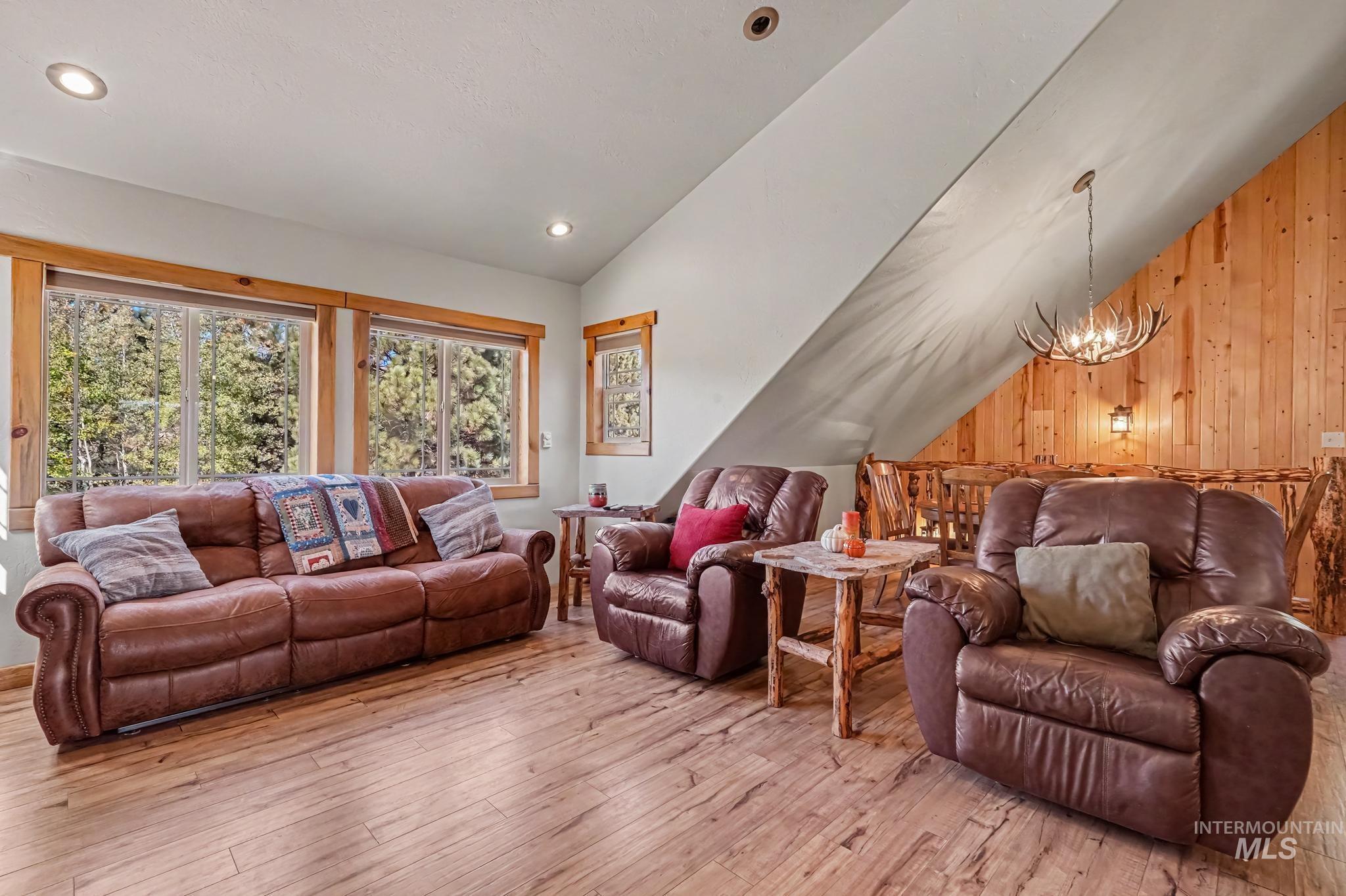106 Wilderness Lake Road Cascade, ID 83611 - Photo 12 of 35 Wood-finish flooring, recessed lighting, wood-paneled accent wall, antler-style chandelier, and natural wood window trim