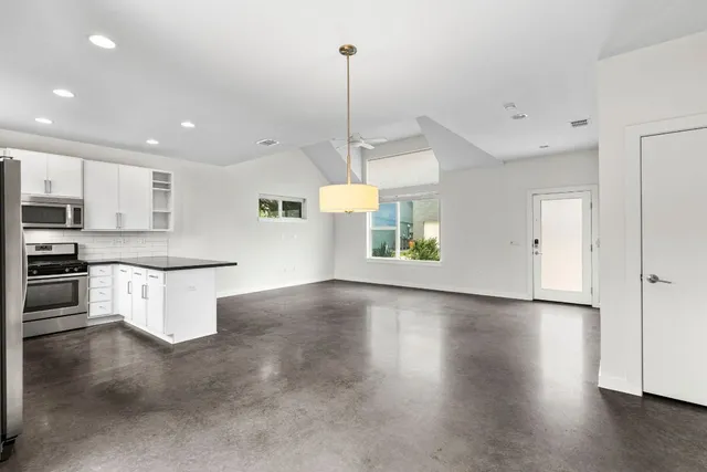 a view of a kitchen with kitchen island a counter top space a sink stainless steel appliances and cabinets