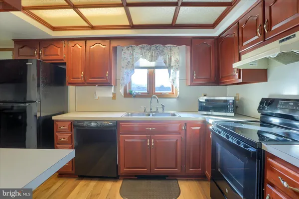 a kitchen with kitchen island granite countertop a sink a counter space appliances and cabinets