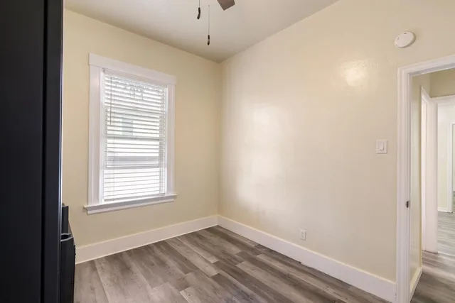 a view of an empty room with wooden floor and a window