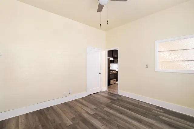 an empty room with wooden floor and windows