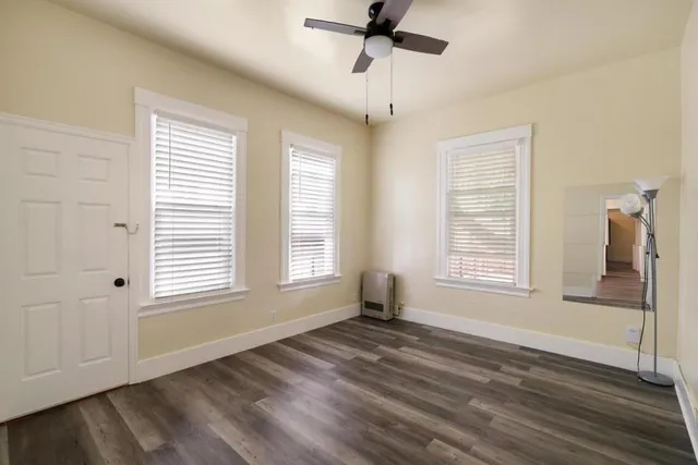 a view of an empty room with wooden floor and a window