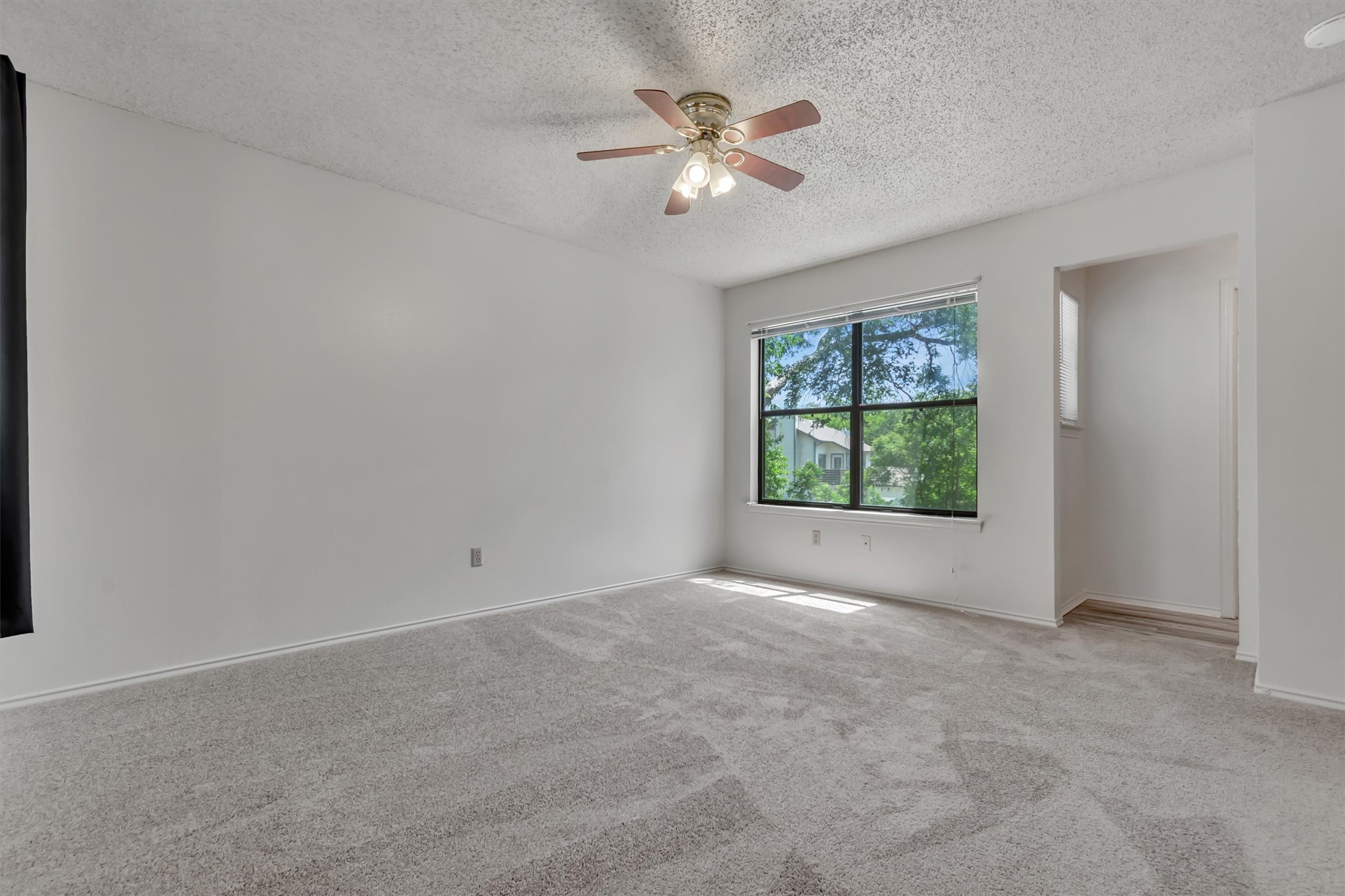 7802 Topawa Cove, Unit B Austin, TX 78729 - Photo 15 of 32 Well-lit spacious bedroom with new carpet, ceiling fan and big window.