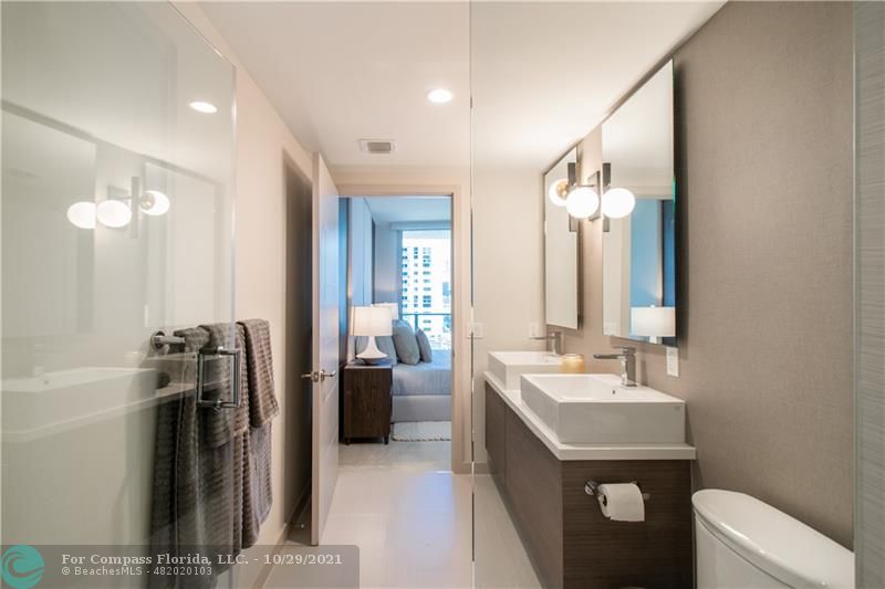 1010 Southwest 2nd Avenue, Unit 804 Miami, FL 33130 - Photo 11 of 12 a bathroom with a double vanity sink a toilet and mirror