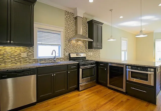 a kitchen with stainless steel appliances granite countertop a sink a stove and a refrigerator
