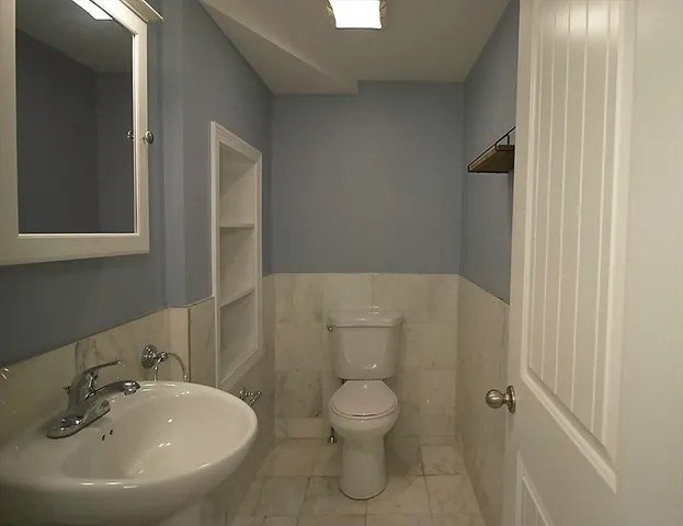 a bathroom with a toilet a sink and mirror