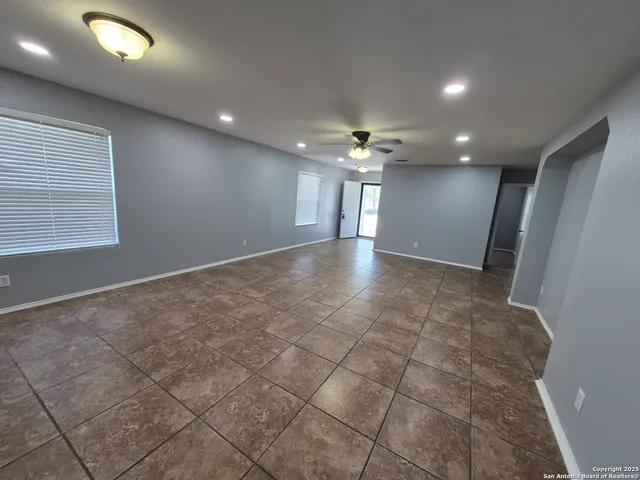 an empty room with kitchen and chandelier fan