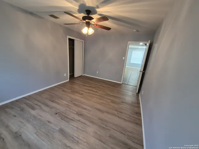 an empty room with wooden floor fan and window