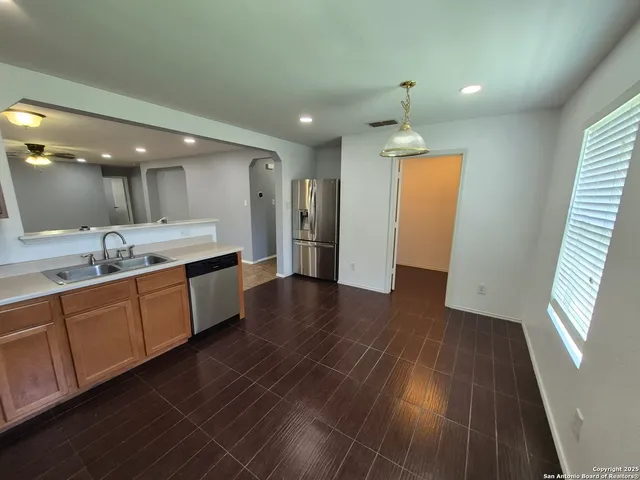 a large kitchen with a sink and dishwasher a stove top oven with wooden floor