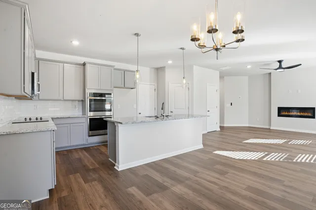 a large kitchen with kitchen island a stove a sink a center island and wooden floor