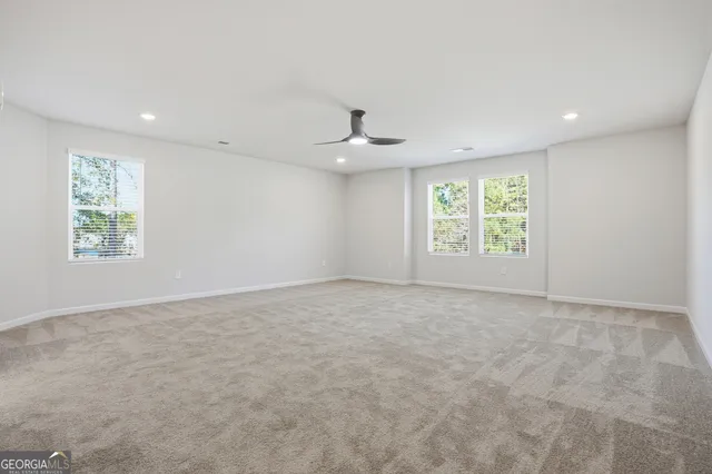 an empty room with windows and ceiling fan